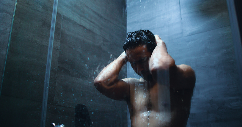 Homme sous la douche se lavant les cheveux, eau ruisselante