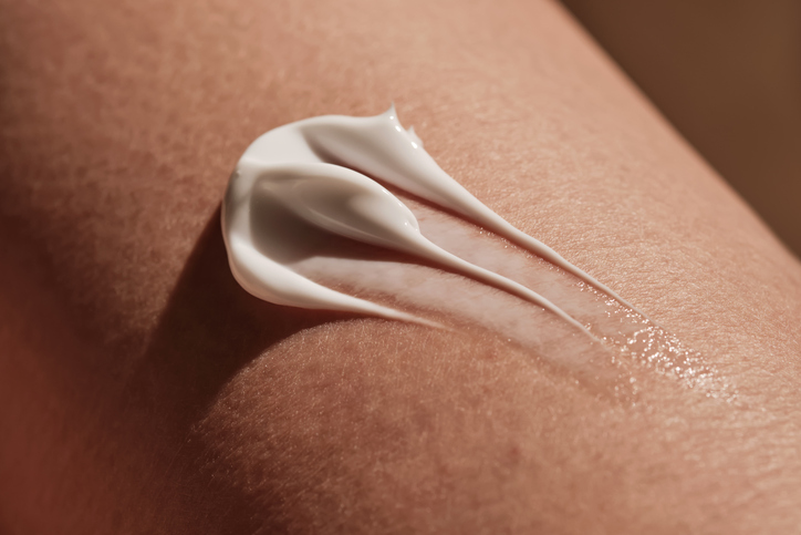 Trait de crème hydratante blanche déposé sur une peau nue